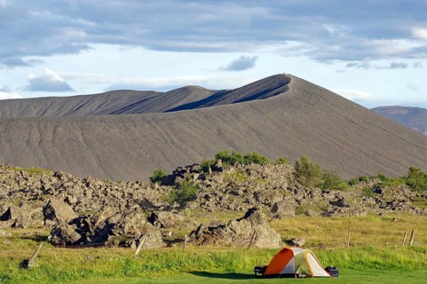 Tent in front of volcanic cone and lava