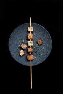 Fried tofu cubes with wooden skewer on plate