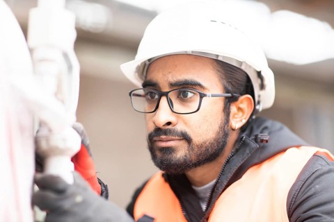 Technician with beard and helmet works in a workshop