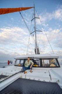 Young man sitting on the deck of a sailing catamaran