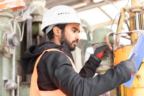 Technician with beard and helmet works in a workshop