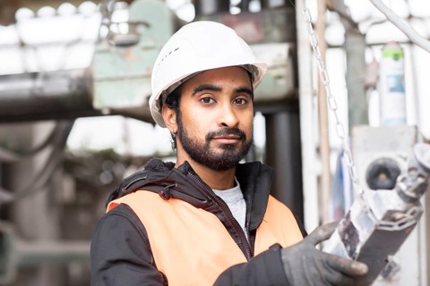 Technician with beard and helmet works in a workshop