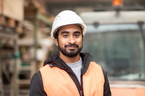 Technician with beard and helmet works in a workshop