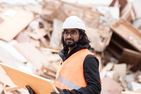 Technician with beard and helmet working in a recycling yard