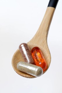 Capsules with food supplement and omega-3 fatty acid in wooden spoon