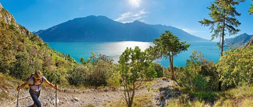 Hiker on the western shore of Lake Garda with the mountain range Monte Baldo