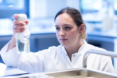 Young lab technician with lab glove and sample working in a lab with lab equipment