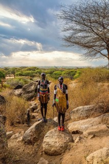 Traditional dressed young girls from the Laarim tribe standing on a rock
