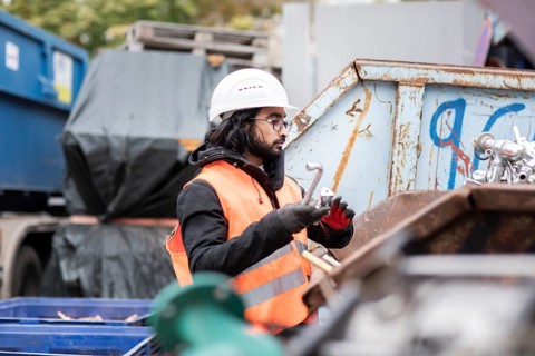 Technician with beard and helmet working in a recycling yard