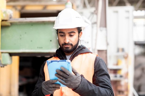Technician with beard and helmet works in a workshop