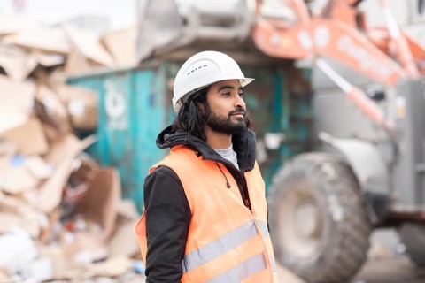 Technician with beard and helmet working in a recycling yard