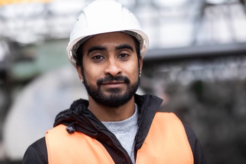 Technician with beard and helmet works in a workshop