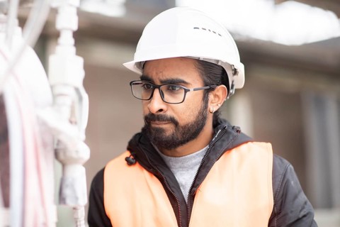 Technician with beard and helmet works in a workshop