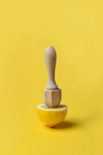 Lemon and lemon squeezer against a yellow background