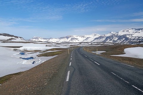 Road leads through barren mountain landscape with snow and ice