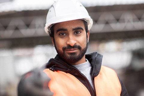 Technician with beard and helmet works in a workshop
