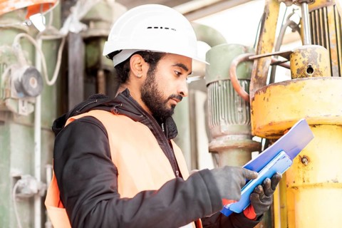 Technician with beard and helmet works in a workshop