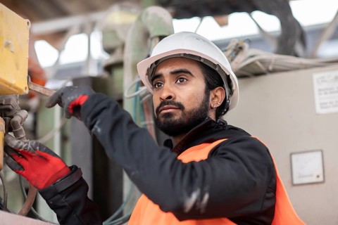 Technician with beard and helmet works in a workshop