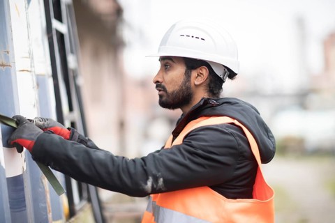 Technician with beard and helmet works in a workshop