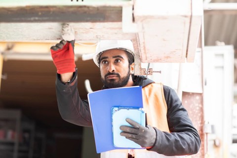 Technician with beard and helmet works in a workshop