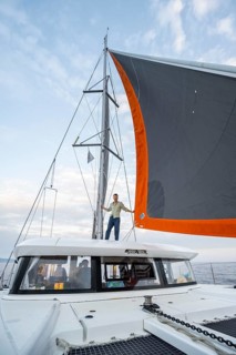 Young man standing between the sails of a sailing catamaran