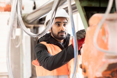 Technician with beard and helmet works in a workshop