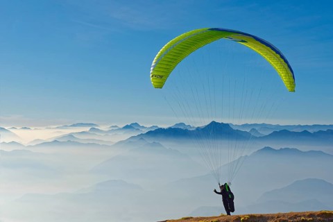 Paraglider taking off with the peaks of the Lake Garda mountains and Bergamo Alps