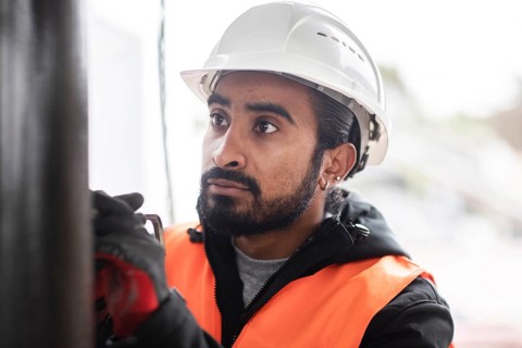 Technician with beard and helmet works in a workshop