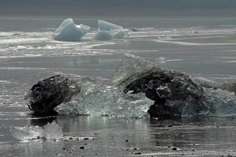 Pieces of ice lying on wide black beach