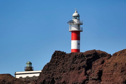 Red and white lighthouse on rocky coast