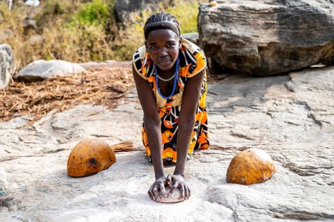 Young girls grinding Sorghum on a rock
