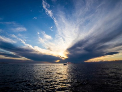 Dark clouds over the sea in front of sunset