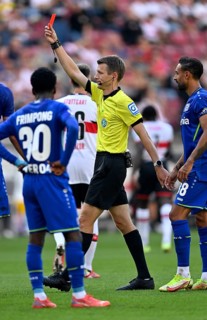Referee Benjamin Cortus reaches into right hip pocket and pulls out red card