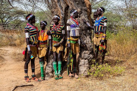 Traditional dressed young girls from the Laarim tribe chatting under a tree