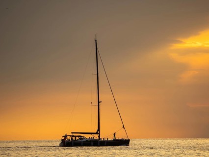 Sailing ship with gathered sails in front of dark clouds