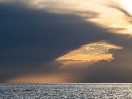 Dark clouds over the sea in front of the setting sun