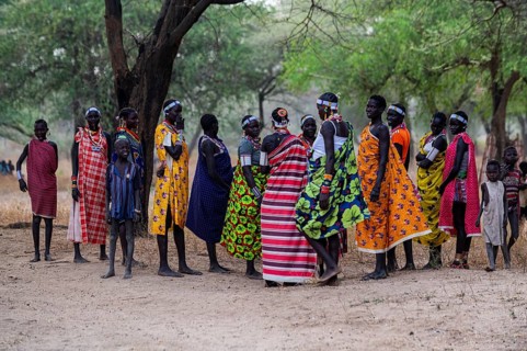 Traditional dressed young girls from the Laarim tribe chatting under a tree