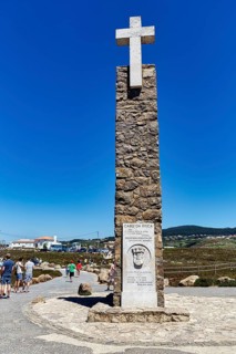 Tourists at the monument with stone cross and information board