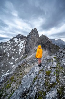 Hiker looking at mountains under dramatic clouds