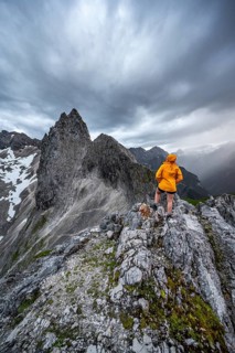 Hiker looking at mountains under dramatic clouds