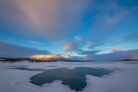 Frozen lake Tornetraesk with snow drifts