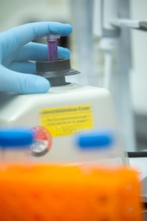 Hand of a medical laboratory assistant holding a reaction vessel in the centrifuge