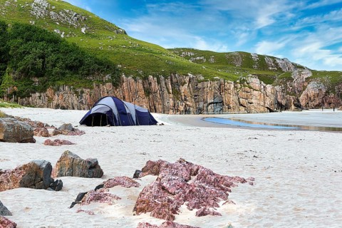 Tent in a bay with rocks and sandy beach