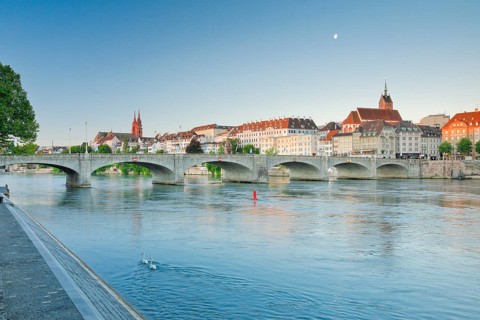 View from the banks of the Rhine along the river promenade to the old town of Basel with the Basel Cathedral