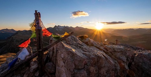 Prayer flags and summit cross on Monte Castellaz at sunset
