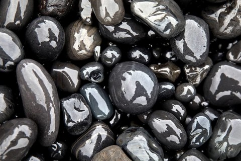 Wet rounded stones with reflection on the beach
