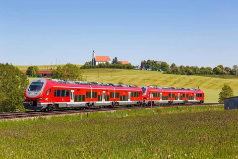 Pesa Link Regional train of Deutsche Bahn DB with church St. Alban in Allgaeu Bavaria in Aitrang