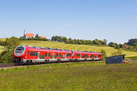 Pesa Link Regional train of Deutsche Bahn DB with church St. Alban in Allgaeu Bavaria in Aitrang