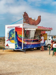 Customers at the food stall labelled Last Bratwurst in front of America