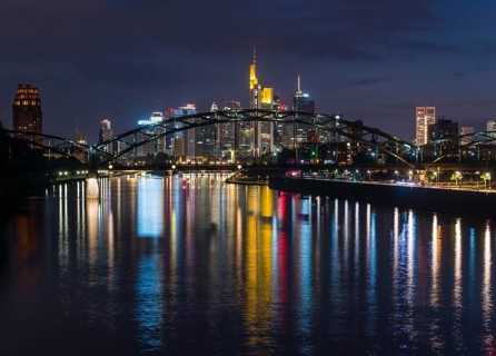 Colourful shining skyline through Deutschherrnbruecke reflected in the Main river during late dusk